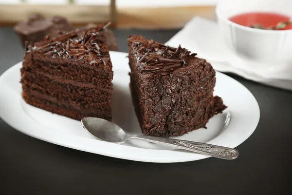 Sliced chocolate cake on wooden table, on light background — Stock Photo, Image