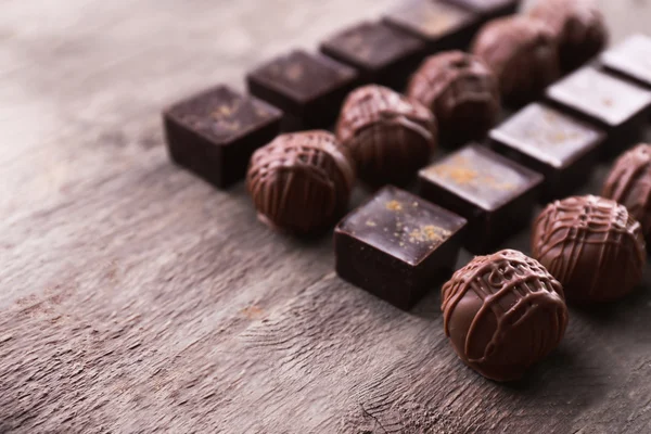 Deliciosos caramelos de chocolate sobre fondo de madera — Foto de Stock