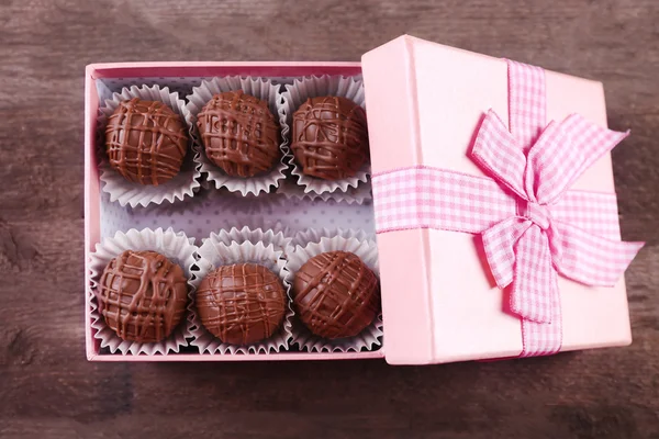 Νόστιμο καραμέλες από σοκολάτα σε ροζ δώρου σε ξύλινα φόντο, κοντινό πλάνο — Φωτογραφία Αρχείου