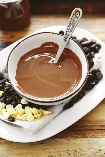 Melted chocolate in bowl, on wooden background — Stock Photo, Image