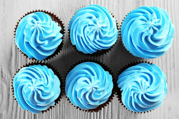 Deliziosi cupcake su sfondo bianco in legno, da vicino — Foto Stock