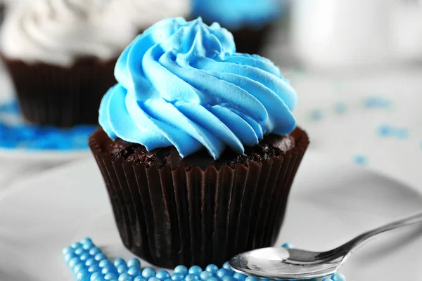 Heerlijke chocolade cupcake met blauwe crème op versierde houten tafel, close-up — Stockfoto