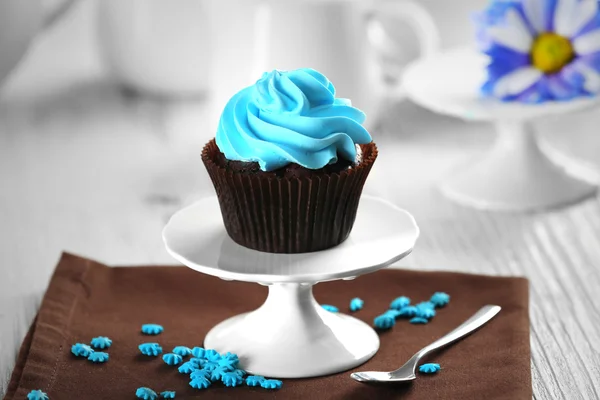 Heerlijke chocolade cupcake met blauwe crème op geserveerd tafel, close-up — Stockfoto