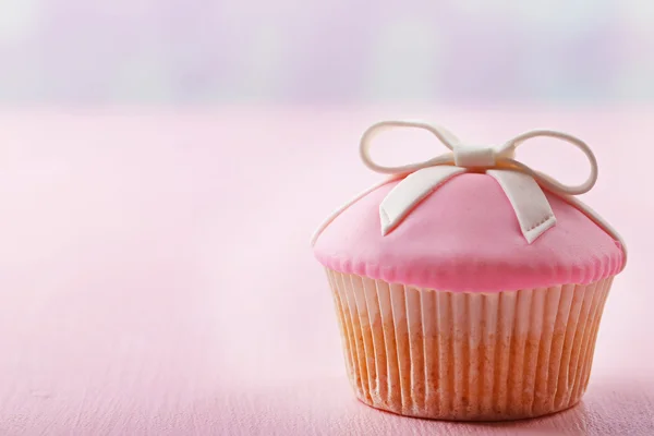 Gâteau savoureux avec arc sur fond en bois de couleur — Photo