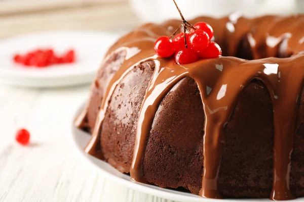 Schokoladenkuchen mit Schneeballbaumbeeren auf Teller auf Tisch — Stockfoto