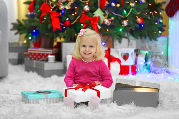 Menina engraçada com caixas de presente e árvore de Natal no fundo — Fotografia de Stock