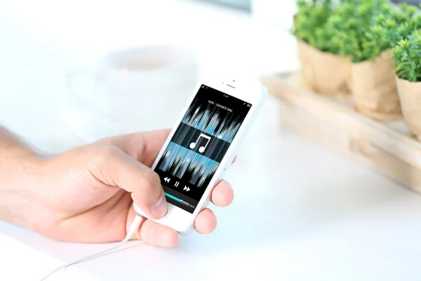 Музыкальный смартфон в мужской руке, на светлом фоне — стоковое фото