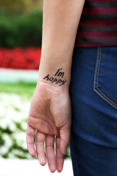 Hand van jonge vrouw met getatoeëerd zin — Stockfoto