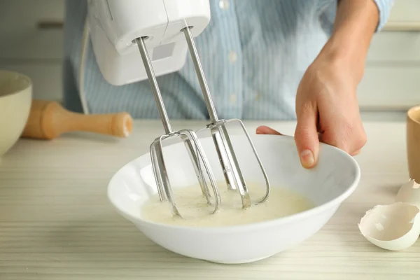 Woman is mixing eggs in a bowl — Stock Photo, Image