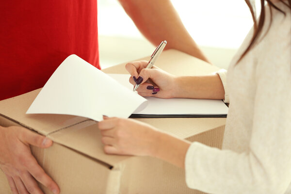 Женщина подписывает расписку о доставке, крупным планом
