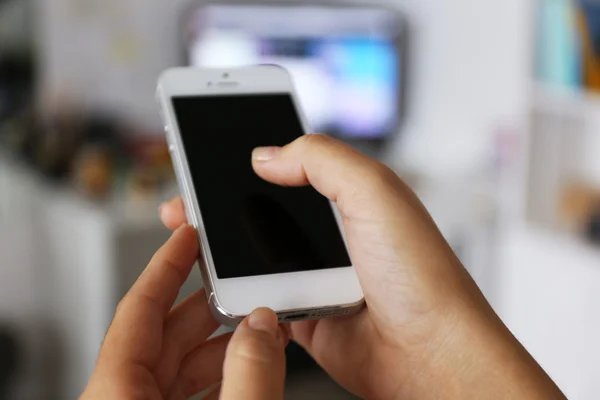 Mulher segurando smartphone dentro de casa — Fotografia de Stock