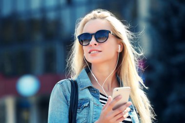 Müzik ve cadde boyunca yürüyen genç kadın