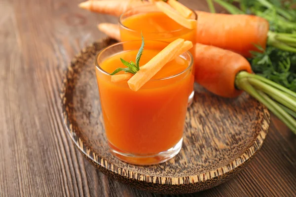 Se acercan los vasos del jugo de zanahoria con hortalizas a la mesa —  Fotos de Stock