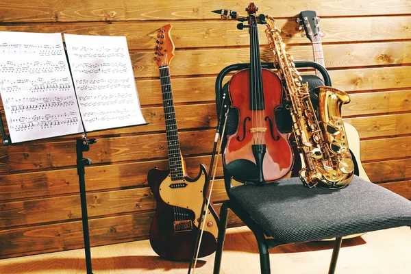 Instruments de musique sur une chaise et porte-notes sur fond de bois — Photo