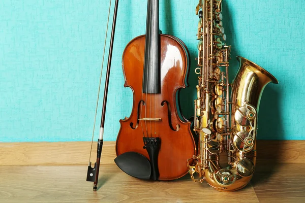 Viool en saxofoon op de vloer tegen blauwe achtergrond — Stockfoto
