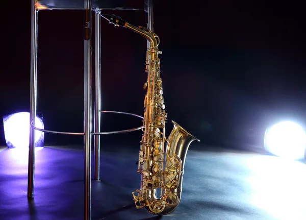 Beautiful golden saxophone near bar stool on a scene — Stock Photo, Image