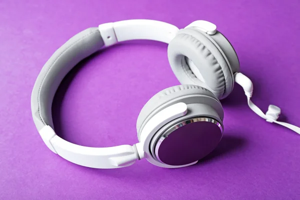 Auriculares blancos y grises sobre fondo morado — Foto de Stock