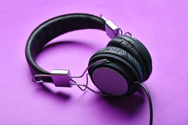 紫蓝色背景上的黑色耳机 — 图库照片