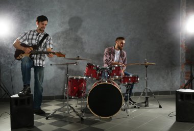 Bateri ve gitar çalmaya müzisyenler