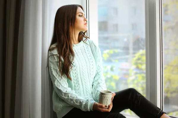 Bella donna seduta sul bordo della finestra con una tazza di caffè — Foto Stock
