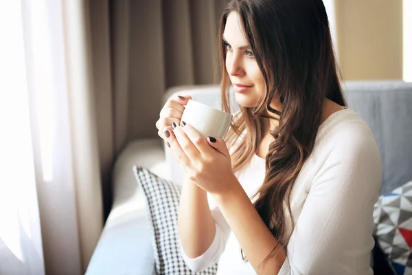 Piękne kobiety na kanapie w pokoju z kubkiem kawy — Zdjęcie stockowe