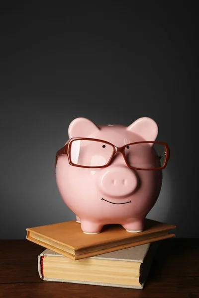 Piggy bank met glazen en boeken — Stockfoto