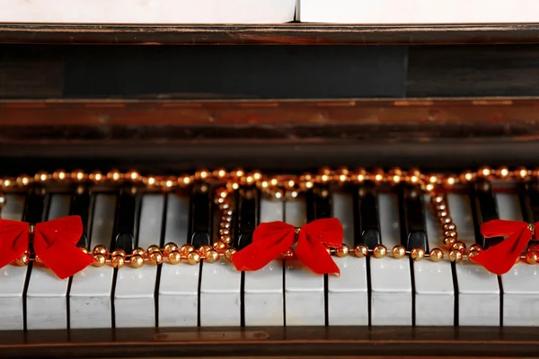 Piano keys decorated with golden Christmas decorations, close up — Stock Photo, Image