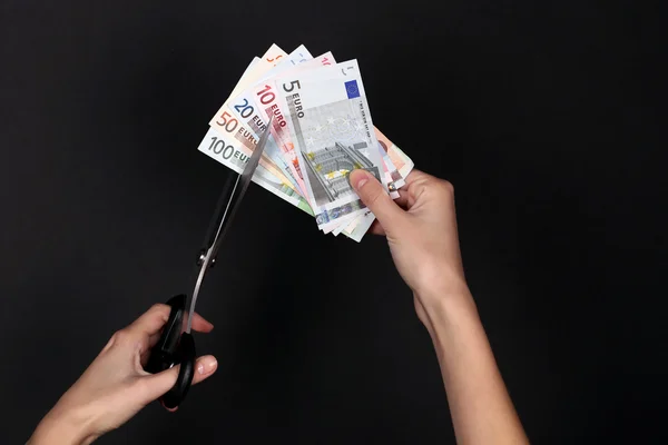 Руки с ножницами, разрезающие банкноты евро — стоковое фото