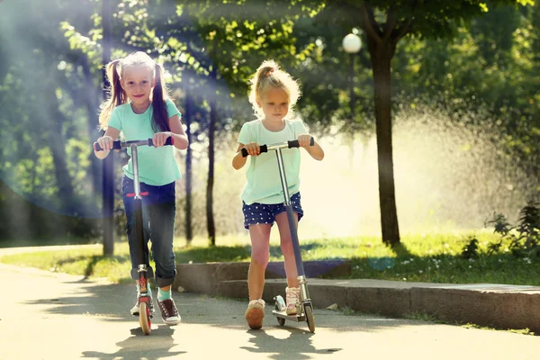 Meninas pequenas montando em scooters — Fotografia de Stock