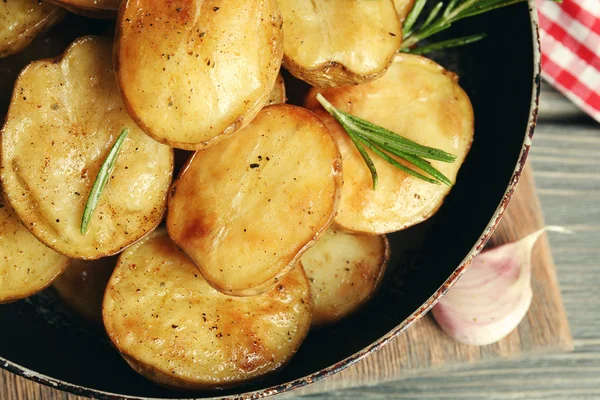 Batata assada deliciosa com alecrim na frigideira na mesa close-up — Fotografia de Stock