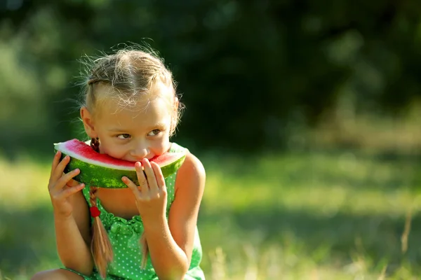 Μικρό κορίτσι που τρώει τα καρπούζια για γκαζόν — Φωτογραφία Αρχείου