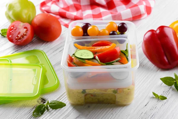 Tasty lunch in plastic containers on wooden table close up — Stock Photo, Image