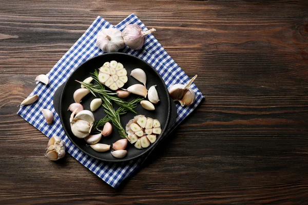 Frischer Knoblauch mit Rosmarin in schwarzer Pfanne — Stockfoto