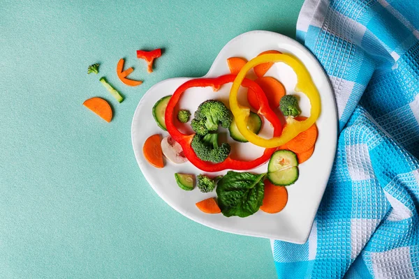 Verduras de redução úteis em uma chapa na forma de coração na vista superior de mesa de madeira — Fotografia de Stock