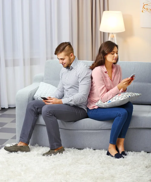 Casal com telefones celulares em casa — Fotografia de Stock