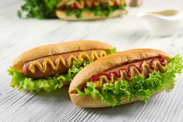 Hot-dogs savoureux sur fond de bois blanc — Photo