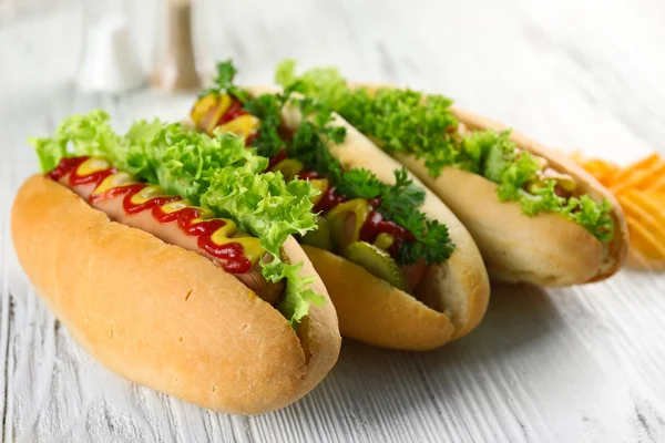 Délicieux hot-dogs avec des chips sur fond de bois blanc, gros plan — Photo