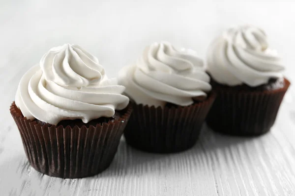 Cupcakes saborosos no fundo de madeira branco, close-up — Fotografia de Stock