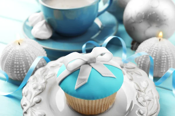 Cupcake saboroso com arco, xícara de café e brinquedos de Natal na cor de fundo de madeira — Fotografia de Stock