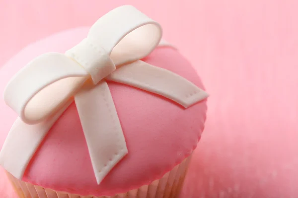 Välsmakande cupcake med rosett på färg trä bakgrund — Stockfoto