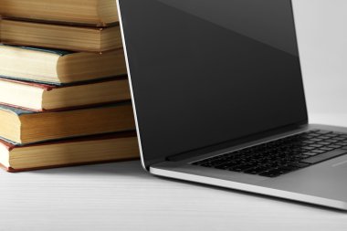 Dizüstü bilgisayar ile kitap yığını