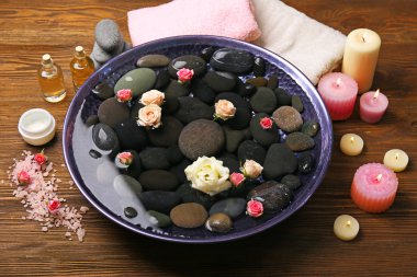 Spa kompozisyon çiçek ve su ahşap arka plan üzerinde taşlar