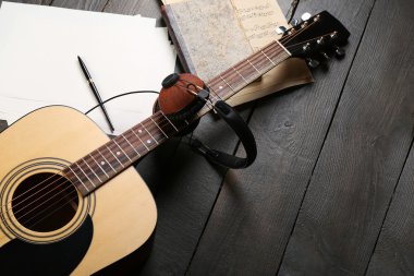 Akustik gitar, kulaklık, nota ve ahşap arka plan üzerinde beyaz evrak