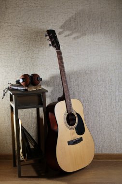Akustik gitar dışkı ve kulaklıktan odasında duvarda propped