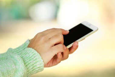 Erkek üzerinde arka plan bulanık bir cep telefonu açık havada tutan eller