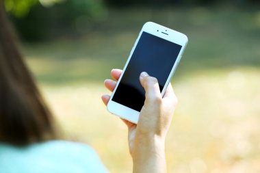 Erkek üzerinde arka plan bulanık bir cep telefonu açık havada tutan eller