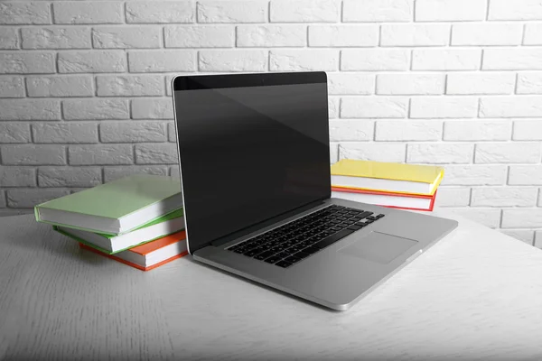 Laptop with books on wall background — Stock Photo, Image