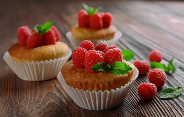 Delicious cupcakes with berries and fresh mint on wooden table close up — Stock Photo, Image