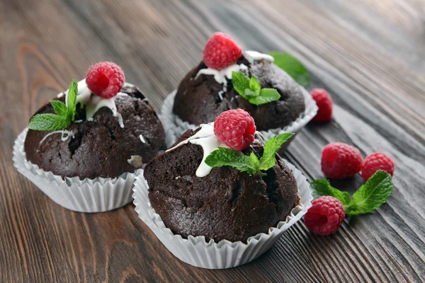 Deliciosos cupcakes de chocolate com bagas e hortelã fresca na mesa de madeira fechar — Fotografia de Stock