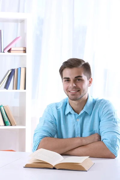 Jeune homme lisant un livre à table — Photo